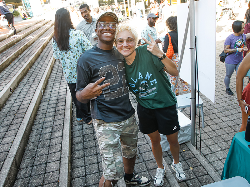 Two Tulanians smile at the camera and flash peace signs at commUNITY 2026.