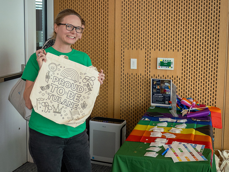 A Tulanian holds up a canvas tote bag that says "Proud to be Tulane".