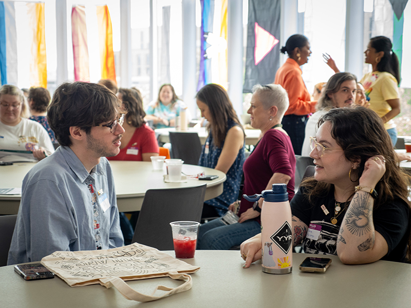 Two Tulanians have a discussion at a table during Pride 2026.