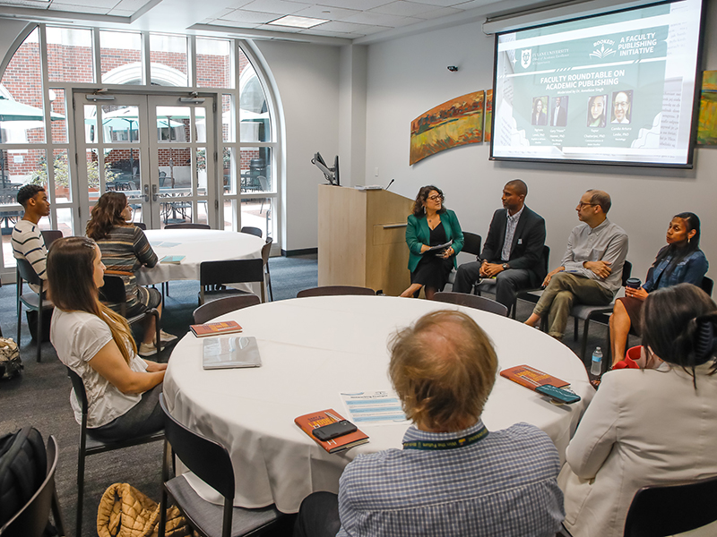 Tulanians sit around tables listening to a panel of speakers at Booked!