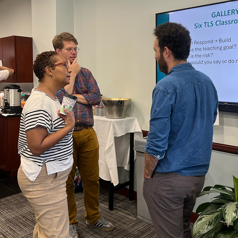 Tulane faculty stand in a circle, conversing after a meeting.