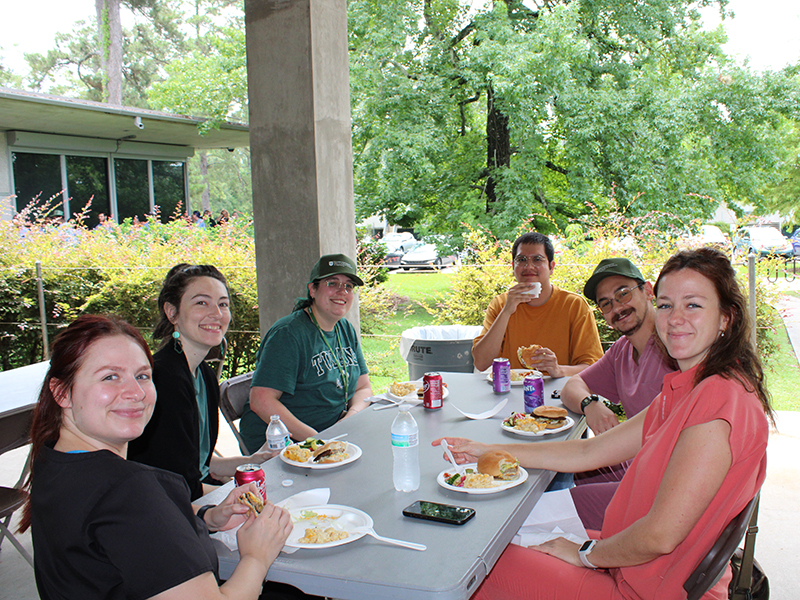 A group of Tulanians sit at a table eating during Juneteenth at the Tulane National Biomedical Research Center.