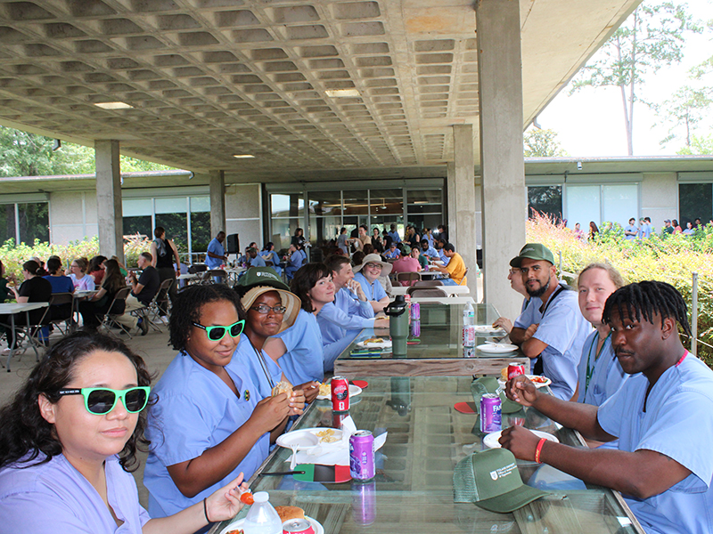 A long table of Tulanians enjoy food at Juneteenth at the Tulane National Biomedical Research Center.