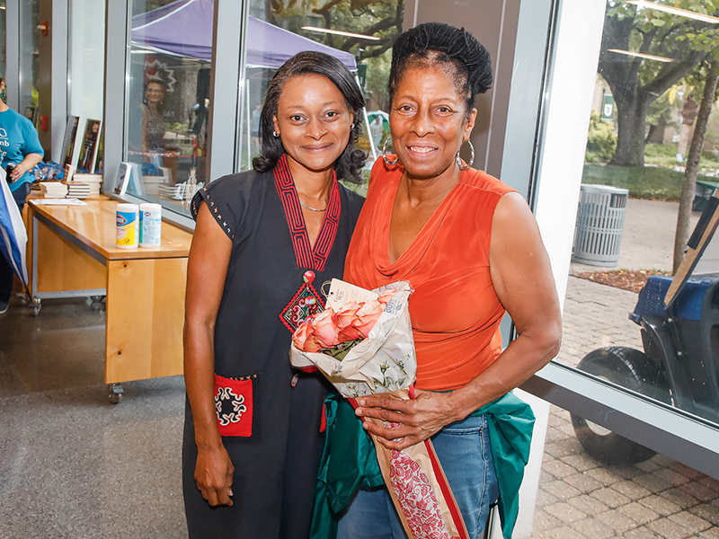 Carolyn Barber-Pierre smiles at the camera and holds a bouquet of flowers with a friend during Juneteenth on Tulane's Uptown campus.