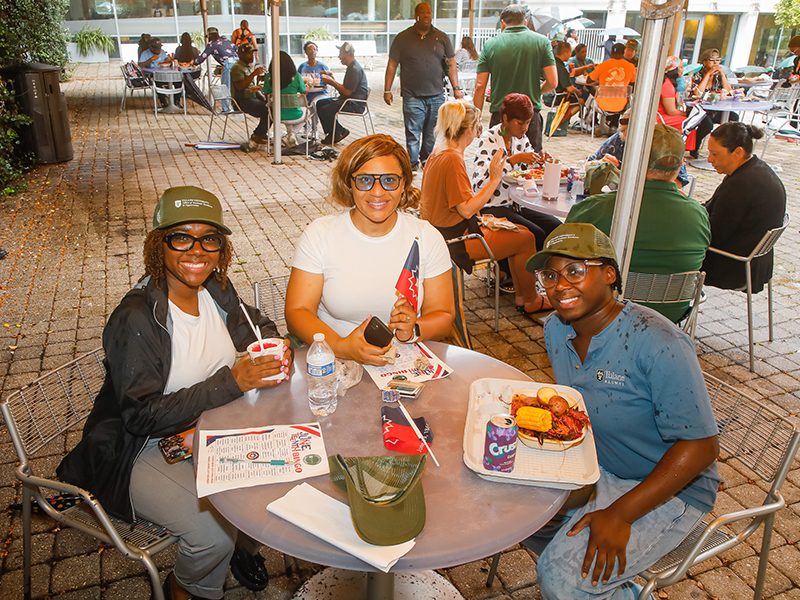 Three Tulanians gather at a table and eat boiled seafood during Juneteenth on Tulane's Uptown campus.