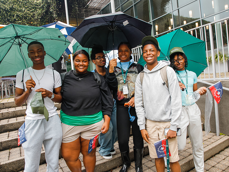 A group of Tulane students holding umbrellas pose for the camera during Juneteenth on Tulane's Uptown campus.