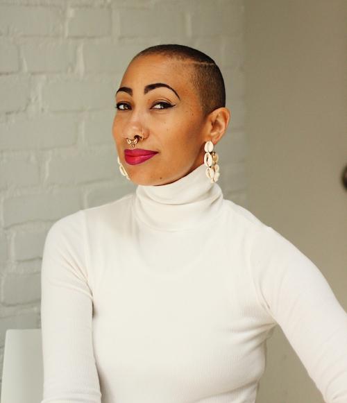 Portrait of Sunni Patterson with a white brick wall behind.